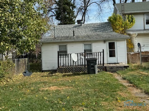 back of property featuring a lawn and a deck