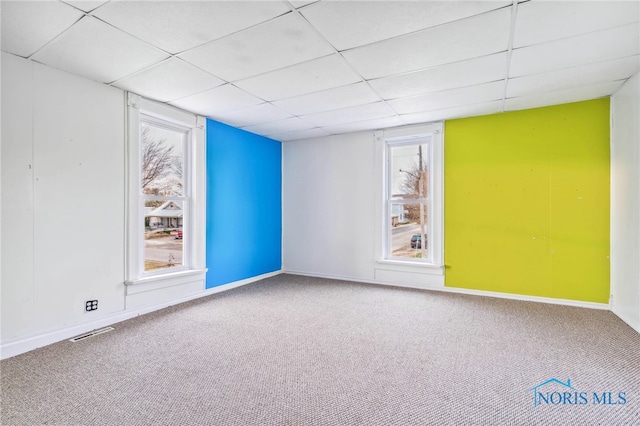 empty room featuring carpet and a paneled ceiling