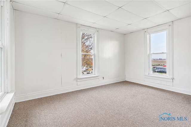 carpeted empty room featuring a paneled ceiling