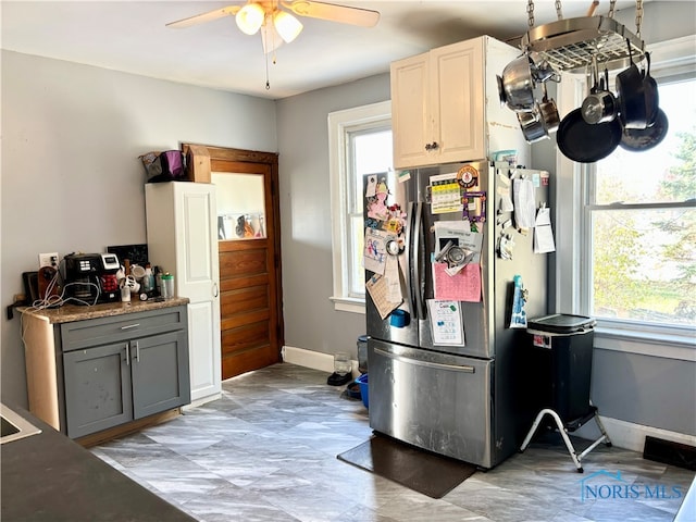 kitchen featuring stainless steel fridge, a wealth of natural light, gray cabinetry, and ceiling fan