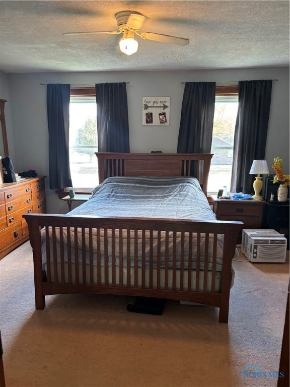 bedroom featuring multiple windows, ceiling fan, light carpet, and a textured ceiling