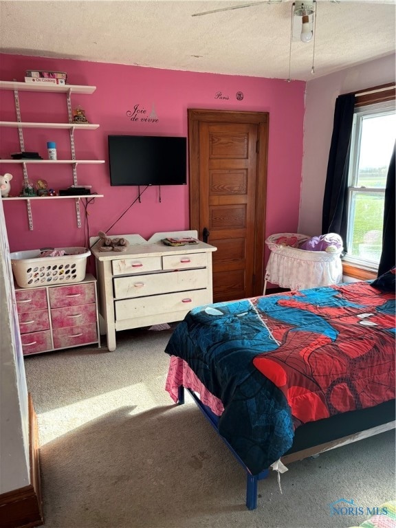 carpeted bedroom featuring ceiling fan and a textured ceiling