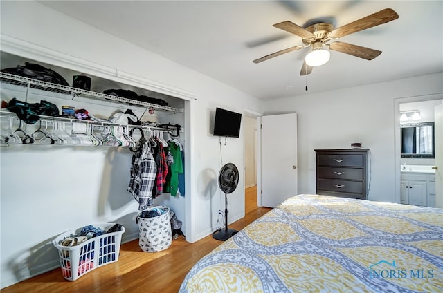 bedroom with ensuite bath, wood-type flooring, ceiling fan, and a closet