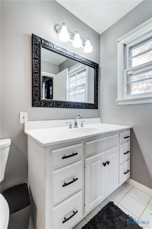 bathroom with toilet, vanity, and tile patterned flooring