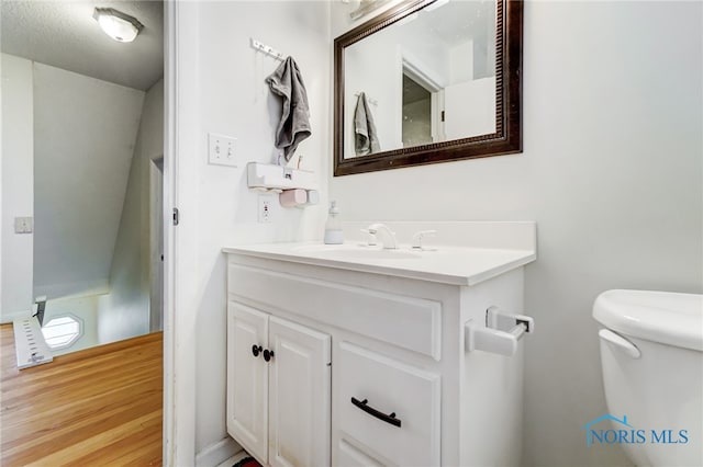 bathroom featuring hardwood / wood-style flooring, vanity, toilet, and a textured ceiling