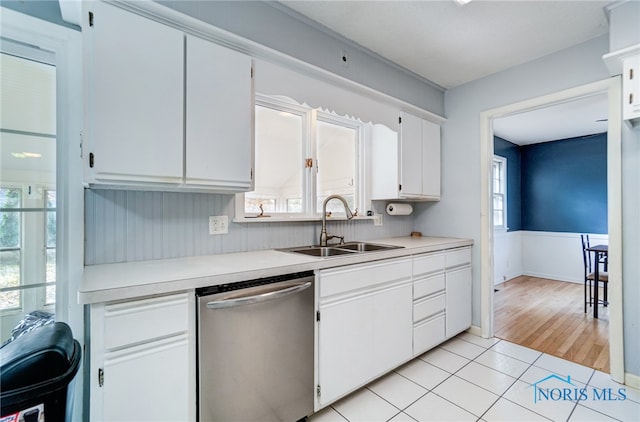 kitchen featuring stainless steel dishwasher, white cabinets, sink, and light hardwood / wood-style flooring