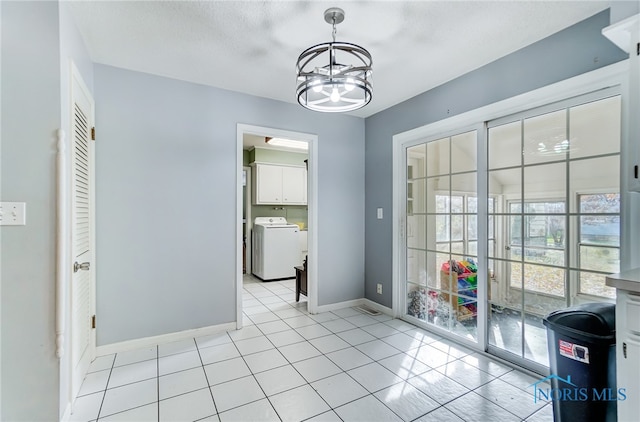 interior space featuring washer / dryer, a chandelier, and light tile patterned floors