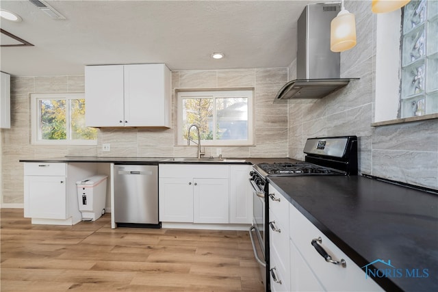 kitchen with light hardwood / wood-style flooring, sink, wall chimney range hood, white cabinetry, and appliances with stainless steel finishes