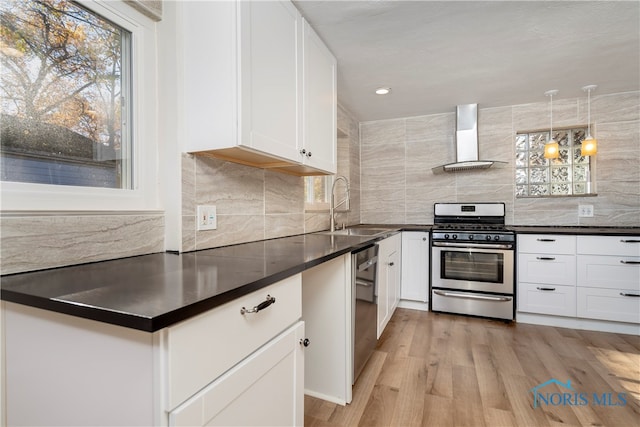 kitchen featuring stainless steel appliances, white cabinetry, sink, wall chimney exhaust hood, and light hardwood / wood-style flooring