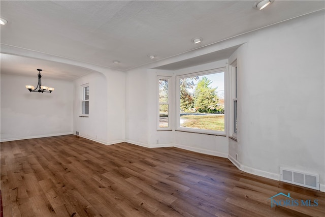 unfurnished room with dark wood-type flooring and an inviting chandelier