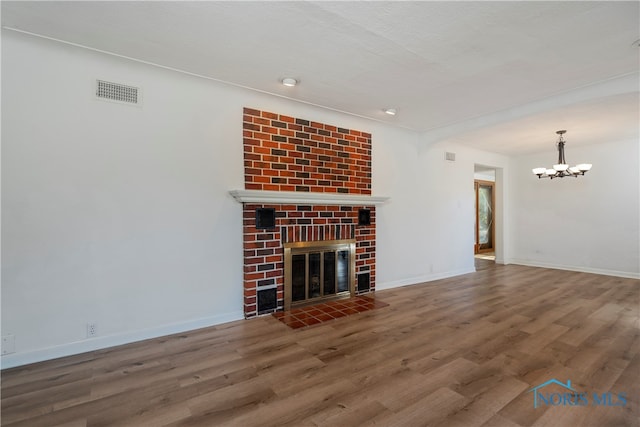 unfurnished living room with a fireplace, wood-type flooring, a textured ceiling, and an inviting chandelier