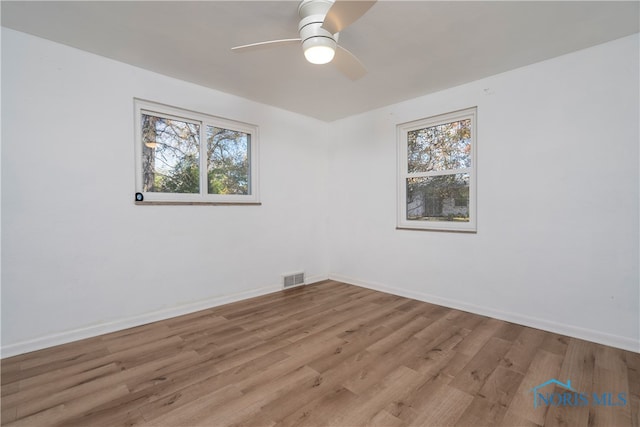 spare room with a wealth of natural light, light hardwood / wood-style floors, and ceiling fan