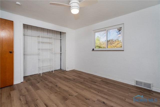 unfurnished bedroom featuring dark wood-type flooring, ceiling fan, and a closet