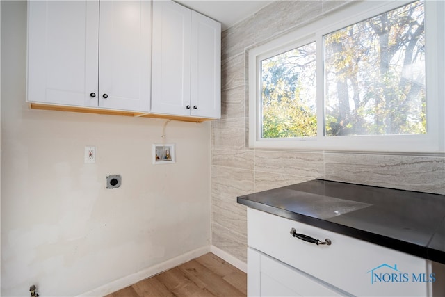 washroom with electric dryer hookup, cabinets, tile walls, washer hookup, and light wood-type flooring