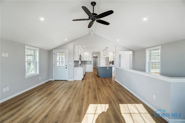 unfurnished living room with light hardwood / wood-style floors, ceiling fan, and lofted ceiling