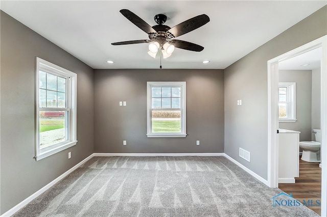 carpeted spare room with plenty of natural light and ceiling fan