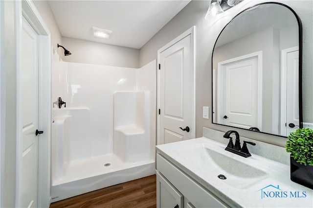 bathroom featuring hardwood / wood-style flooring, vanity, and walk in shower