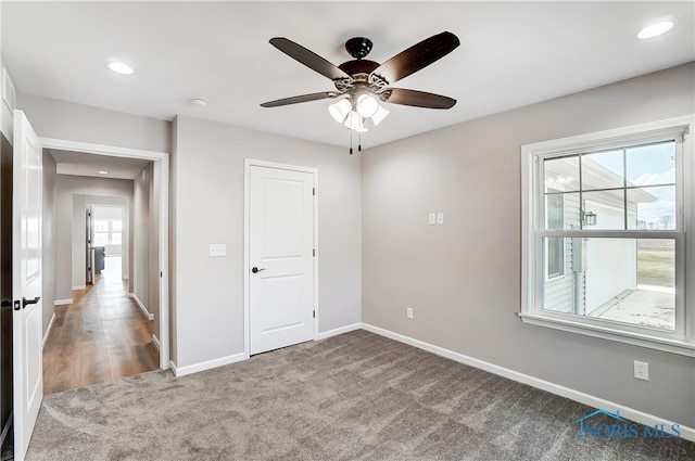 unfurnished bedroom with carpet floors, a closet, multiple windows, and ceiling fan