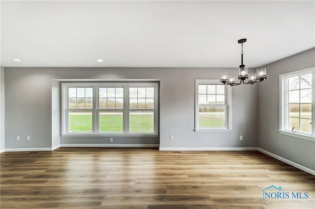 empty room featuring an inviting chandelier and hardwood / wood-style flooring