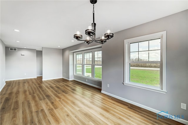 spare room with wood-type flooring and an inviting chandelier