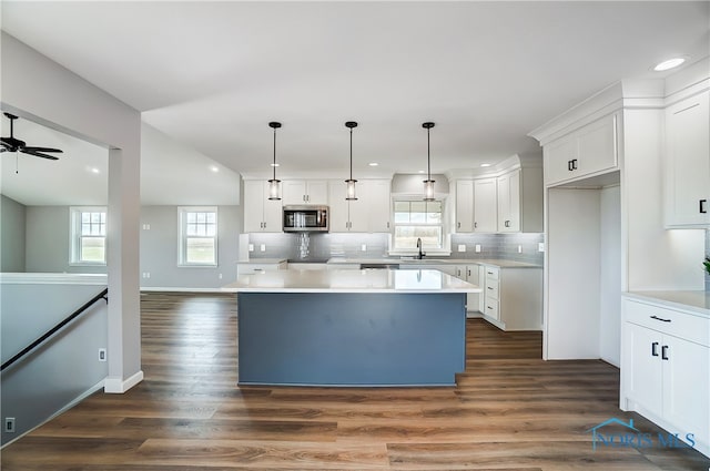 kitchen with a center island, white cabinets, tasteful backsplash, decorative light fixtures, and dark hardwood / wood-style flooring