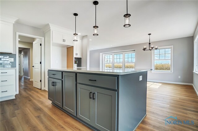 kitchen with gray cabinetry, tasteful backsplash, pendant lighting, white cabinets, and hardwood / wood-style flooring