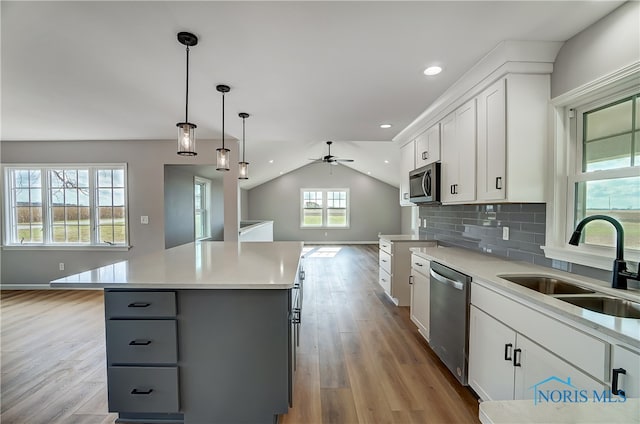 kitchen featuring appliances with stainless steel finishes, gray cabinetry, sink, white cabinets, and a kitchen island