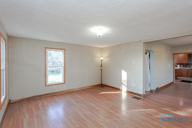 empty room featuring a textured ceiling and light hardwood / wood-style flooring