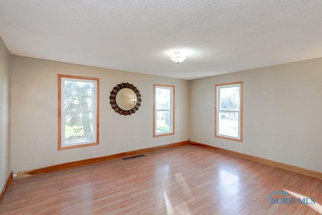 unfurnished room with a textured ceiling and light hardwood / wood-style floors