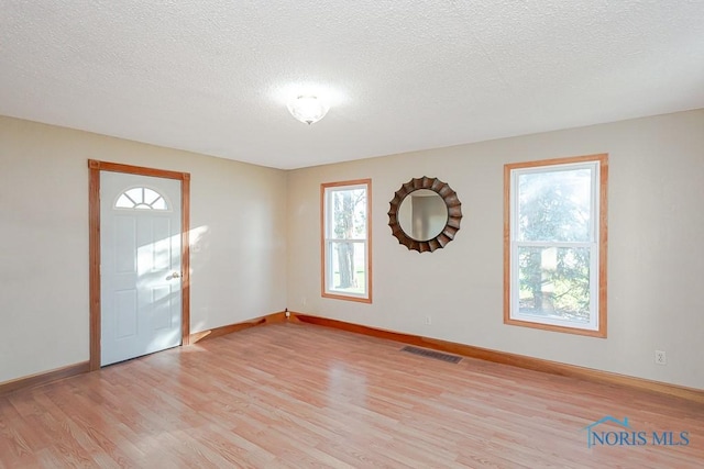 foyer entrance featuring light hardwood / wood-style floors and a textured ceiling