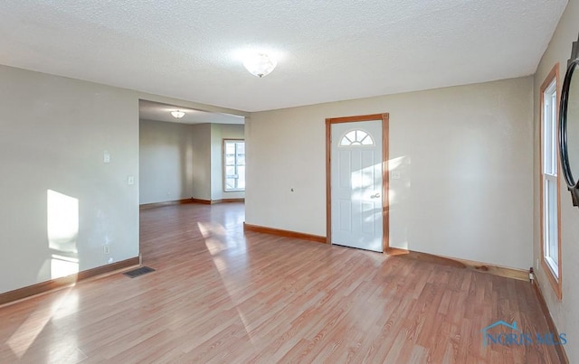 interior space featuring light wood-type flooring and a textured ceiling