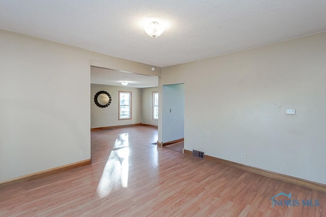 unfurnished room featuring a textured ceiling and light wood-type flooring