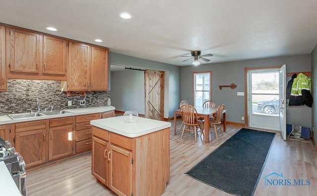 kitchen featuring a center island, a barn door, light wood-type flooring, and sink