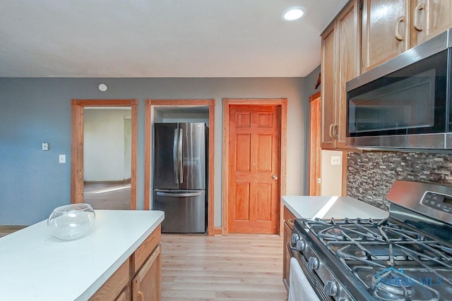 kitchen with light wood-type flooring, stainless steel appliances, light brown cabinetry, and tasteful backsplash