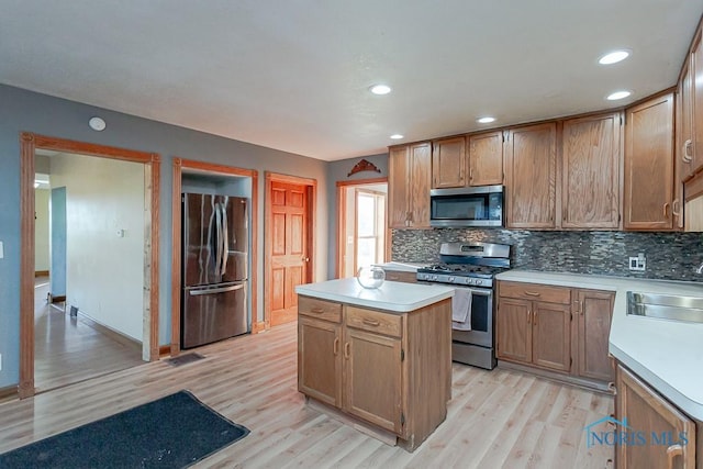 kitchen with decorative backsplash, stainless steel appliances, sink, light hardwood / wood-style flooring, and a kitchen island