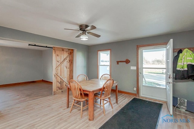 dining room featuring light hardwood / wood-style floors, a barn door, and a healthy amount of sunlight