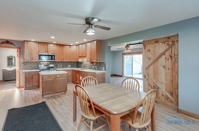 kitchen featuring a barn door, light wood-type flooring, tasteful backsplash, a kitchen island, and stainless steel appliances