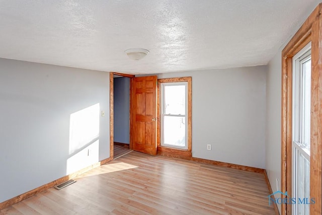 empty room featuring a textured ceiling and light hardwood / wood-style flooring