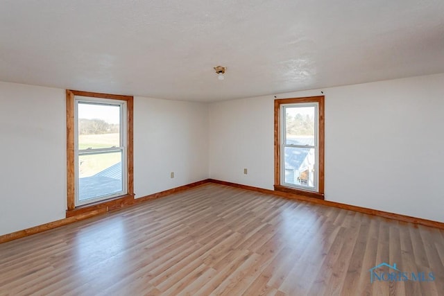 unfurnished room with vaulted ceiling, light hardwood / wood-style flooring, and a wealth of natural light