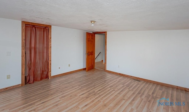 spare room featuring a textured ceiling and light hardwood / wood-style flooring