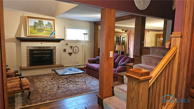 living room with hardwood / wood-style floors, baseboard heating, crown molding, and a brick fireplace