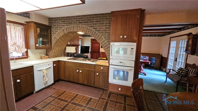 kitchen featuring sink, white appliances, french doors, and brick wall