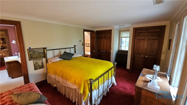 bedroom with ornamental molding, dark colored carpet, and multiple closets