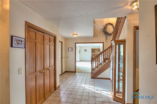 hall with light tile patterned floors and a textured ceiling