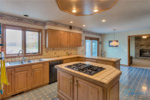 kitchen with dishwasher, sink, stainless steel gas cooktop, tile countertops, and a kitchen island