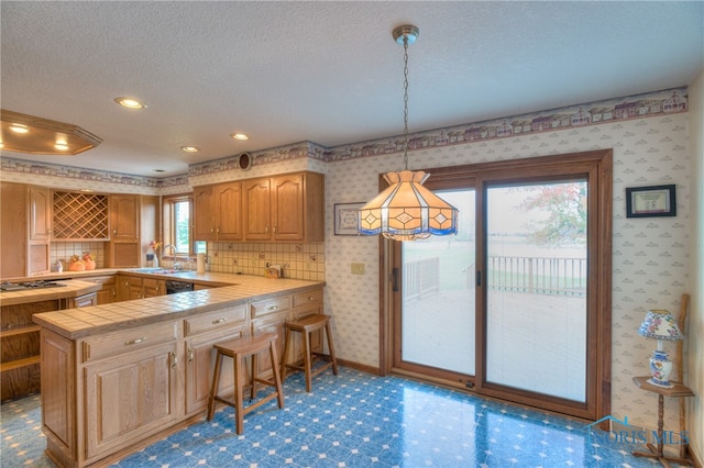 kitchen featuring kitchen peninsula, a textured ceiling, plenty of natural light, and hanging light fixtures