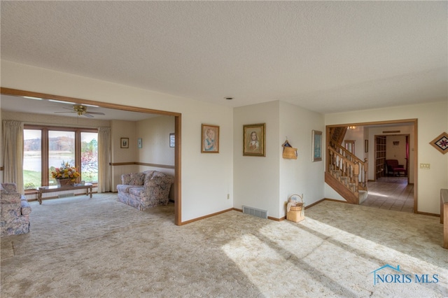 unfurnished living room with ceiling fan, carpet floors, and a textured ceiling