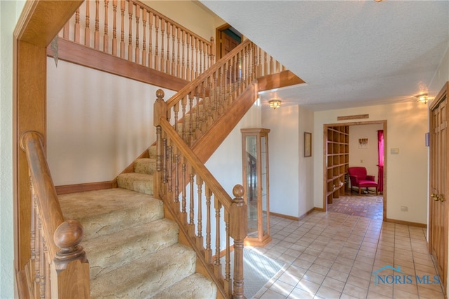 staircase featuring tile patterned flooring and a textured ceiling