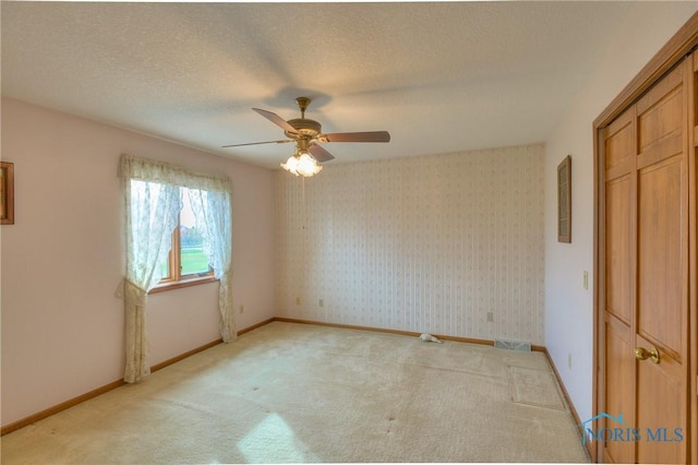 7733 Brown Rd, Curtice, OH 43412 - unfurnished bedroom with light colored carpet, a ceiling fan, baseboards, and a textured ceiling