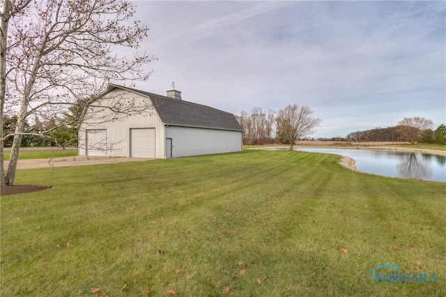 view of yard featuring a water view, a garage, and an outdoor structure